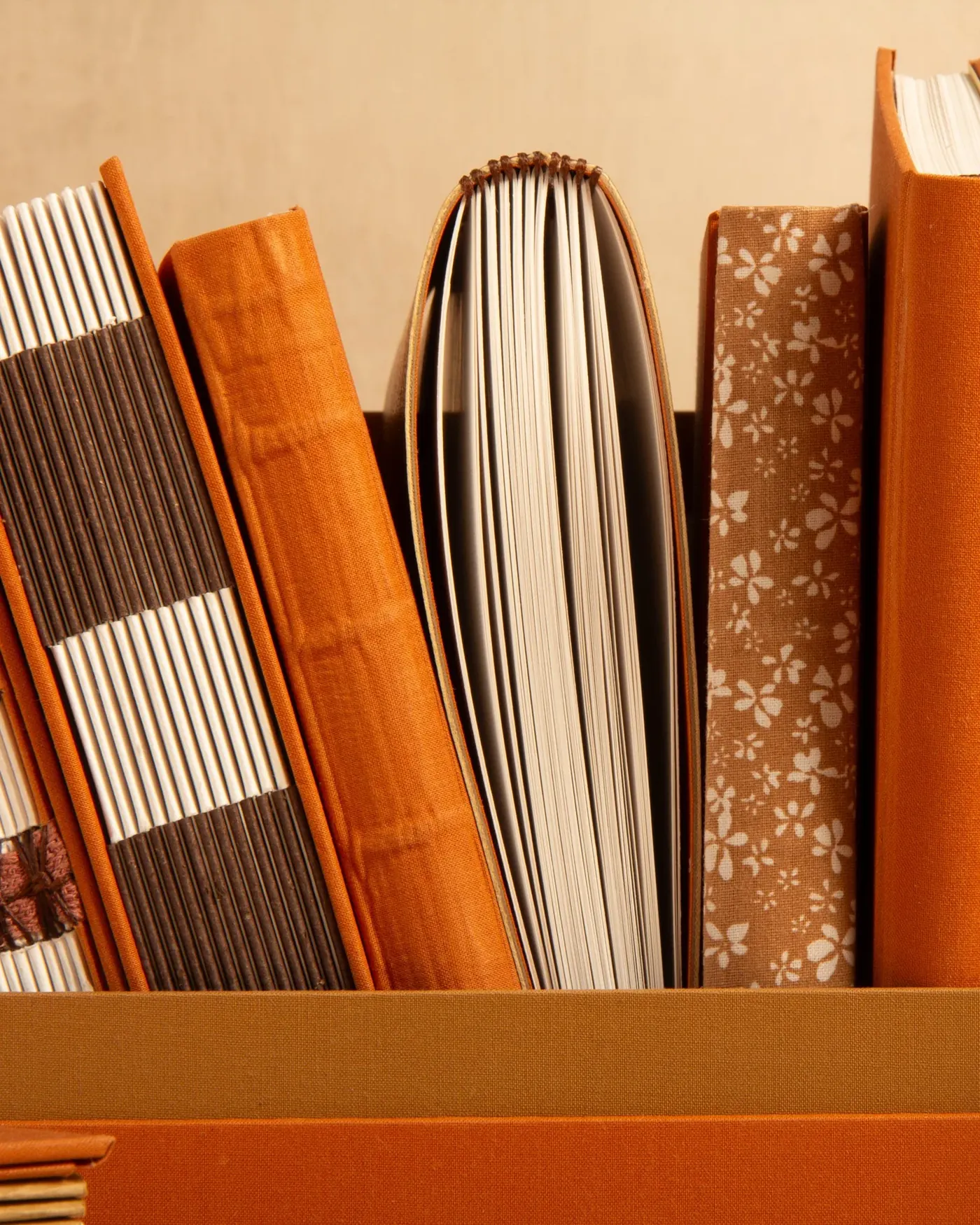 A row of orange and patterned notebooks on a shelf